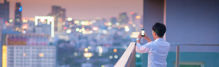 Man focusing smartphone on a city of lights
