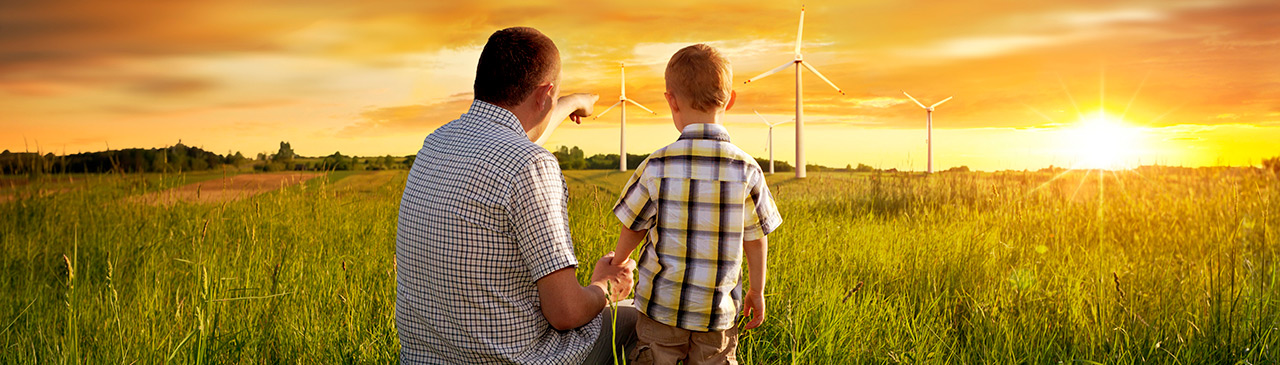 Father and son looking at wind turbines on the horizon