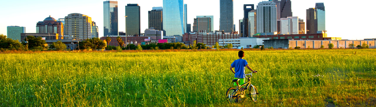 Child holding bike looking at Houston, Texas skyline.