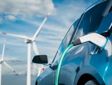 Electric vehicle charging with wind turbines in the background