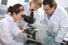 A group of scientists looking at a microscope