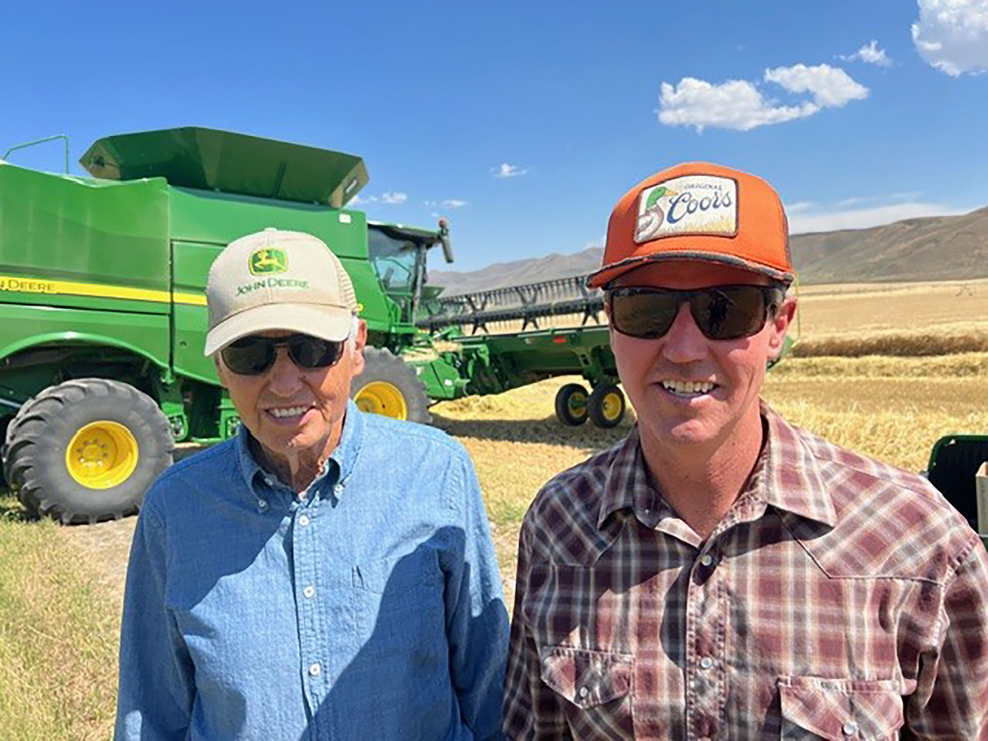  Farmer Justin Stevenson smiles to the camera while standing in front of machinery in a farm field.
