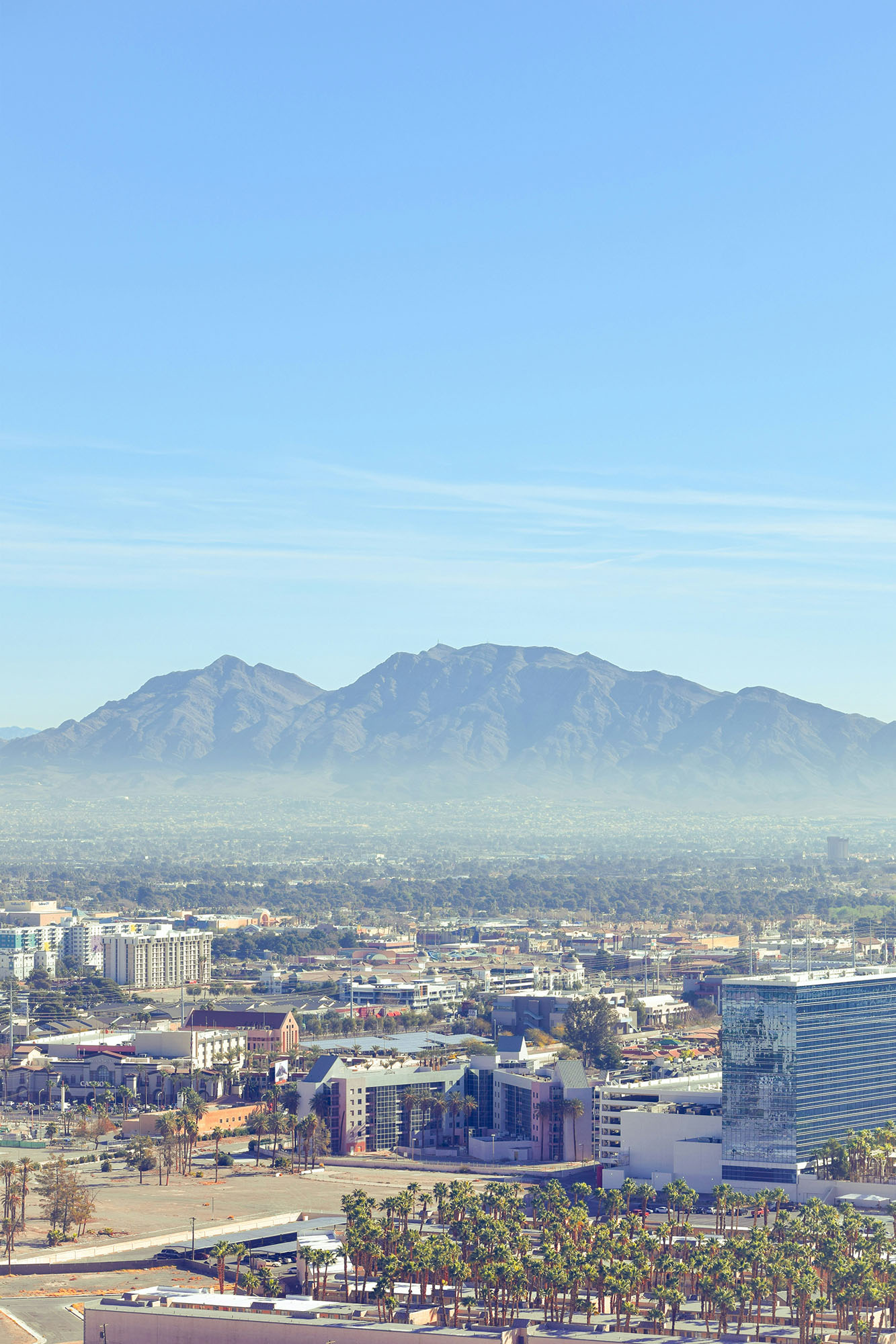 Wide view of buildings in downtown Las Vegas and the surrounding mountains with a haze over the area.