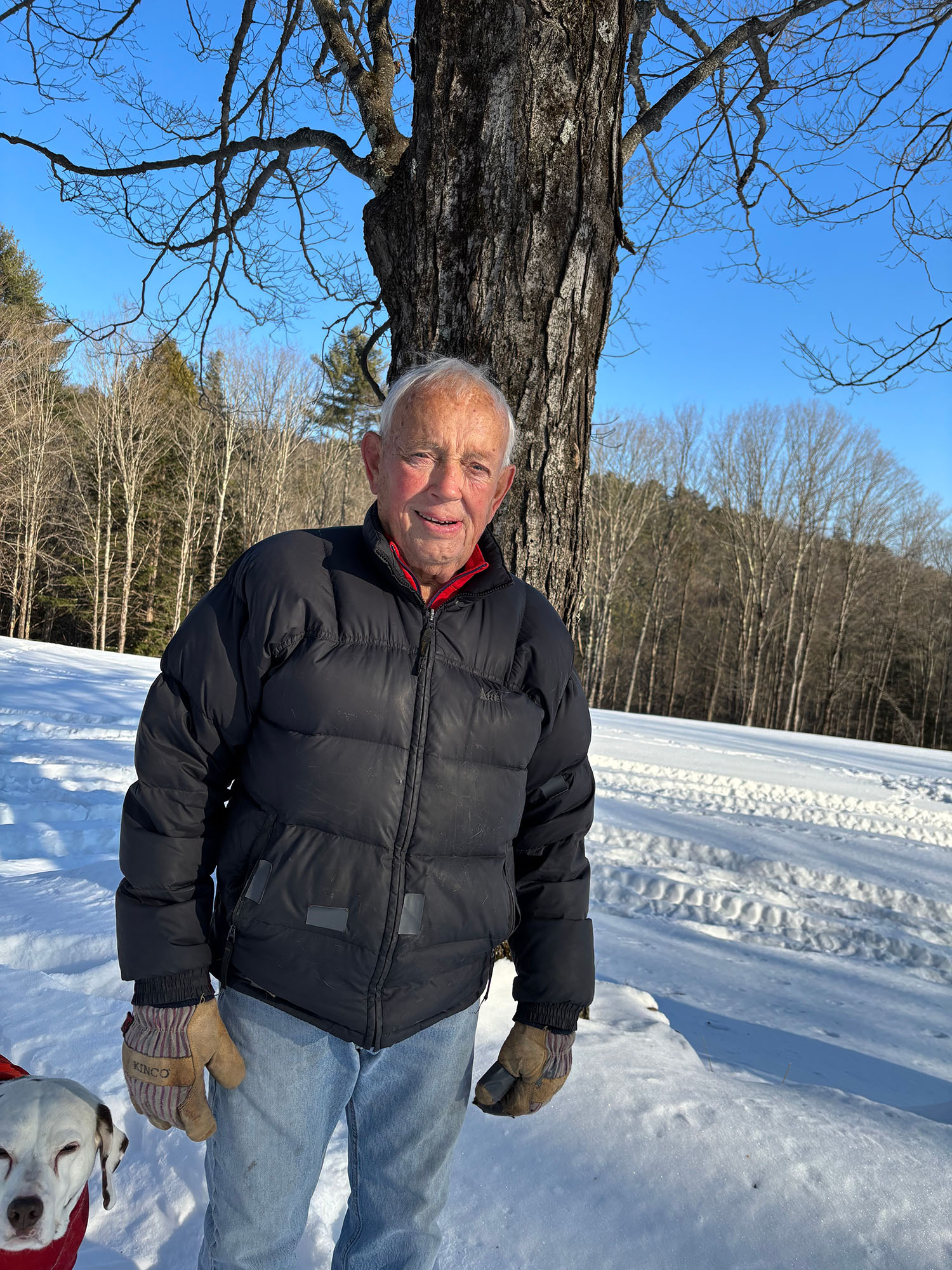 Bill Stilson on his farm in Vermont wearing a puffer jacket and work gloves.
