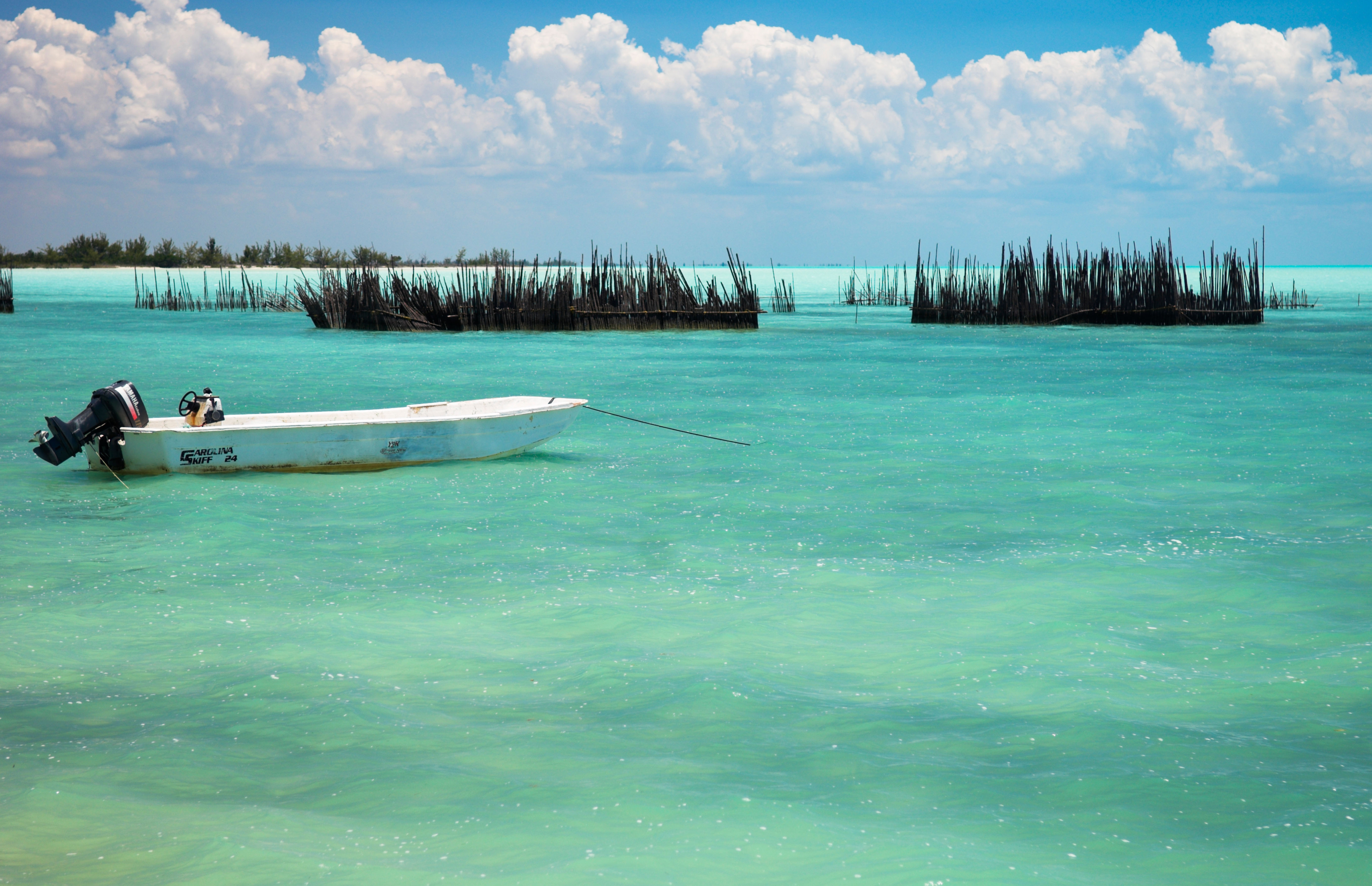 One small pleasure fishing boat and fish pens on calm turquoise blue sea north side Andros Island Bahamas