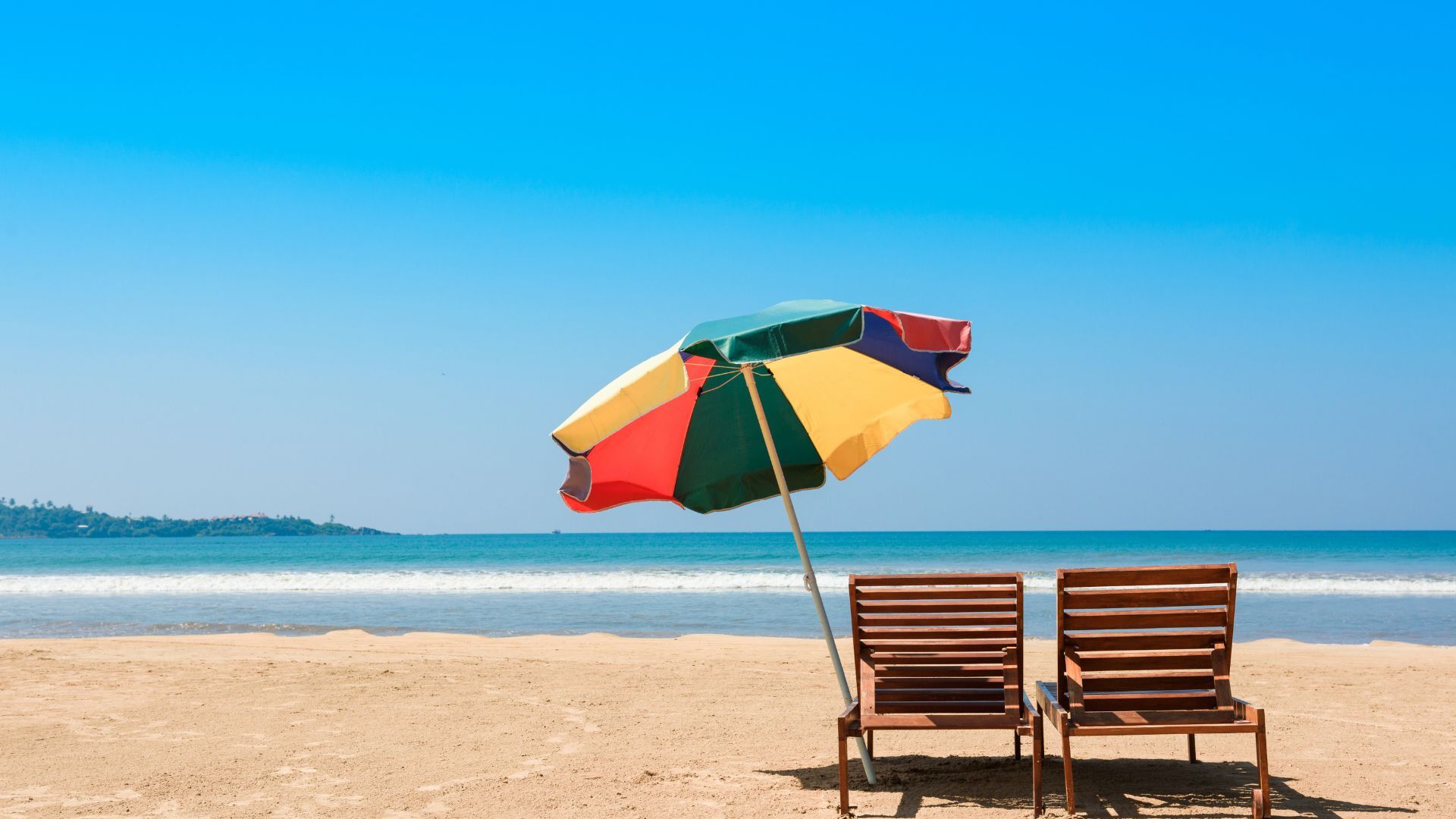 Two beach chairs on a sandy beach looking out over a blue ocean