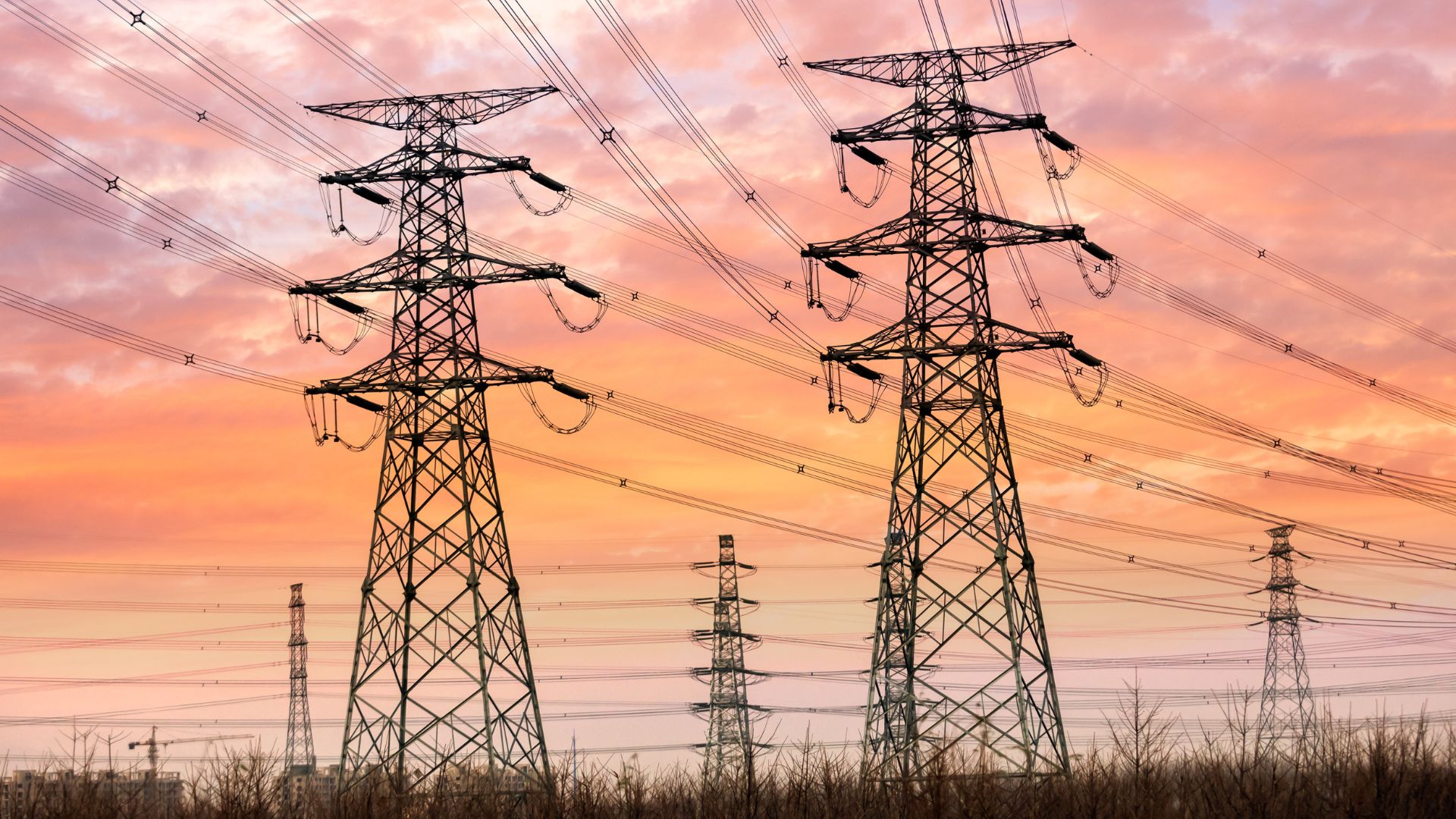 Transmission towers with lots of power lines running to them at dusk