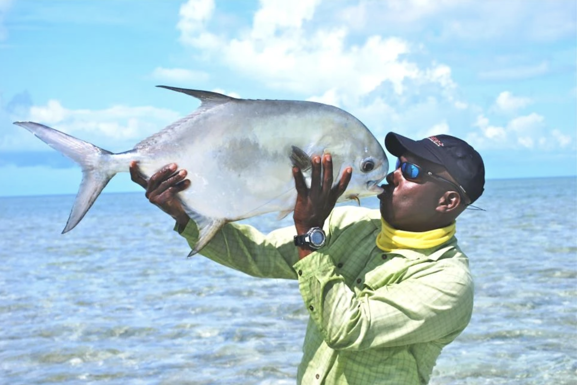 Fishing guide Prescott Smith kisses his prize -- a tall, flat, silvery gamefish called a permit.