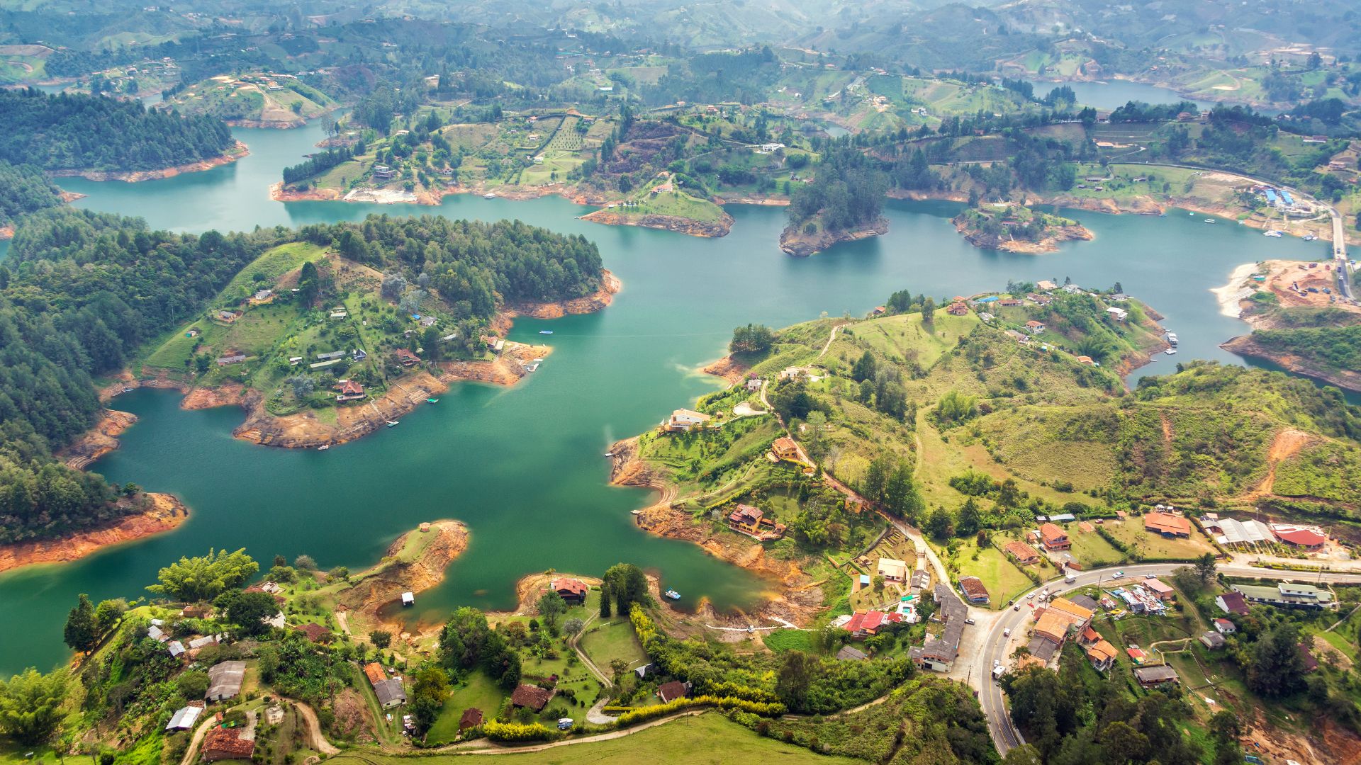 A high-up shot of a lake surrounded by lots of green hills