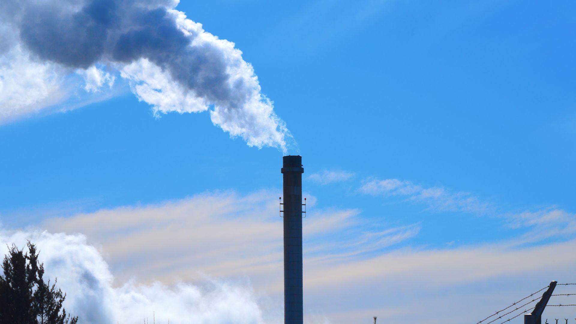 A smokestack with white smoke billowing out