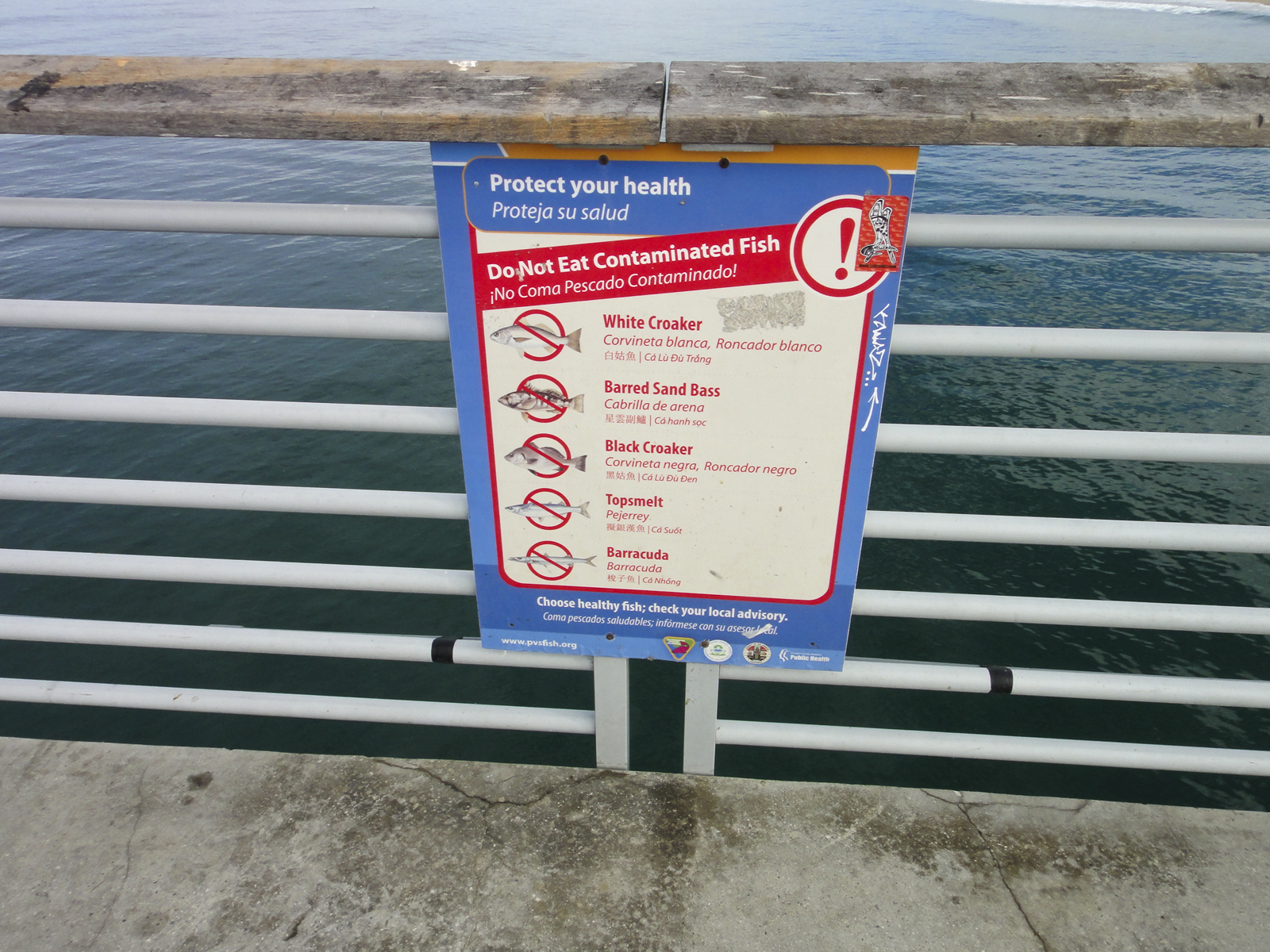 A sign attached to a pier warning of the dangers of eating contaminated fish
