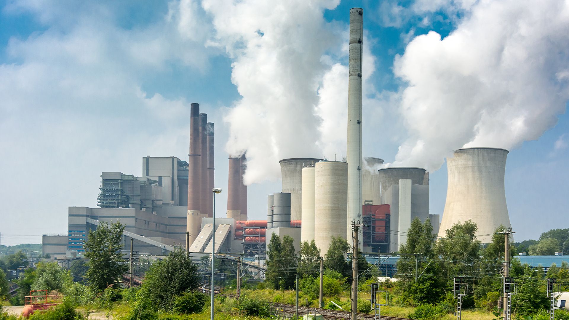 A city skyline in the background with a power plant in the foreground