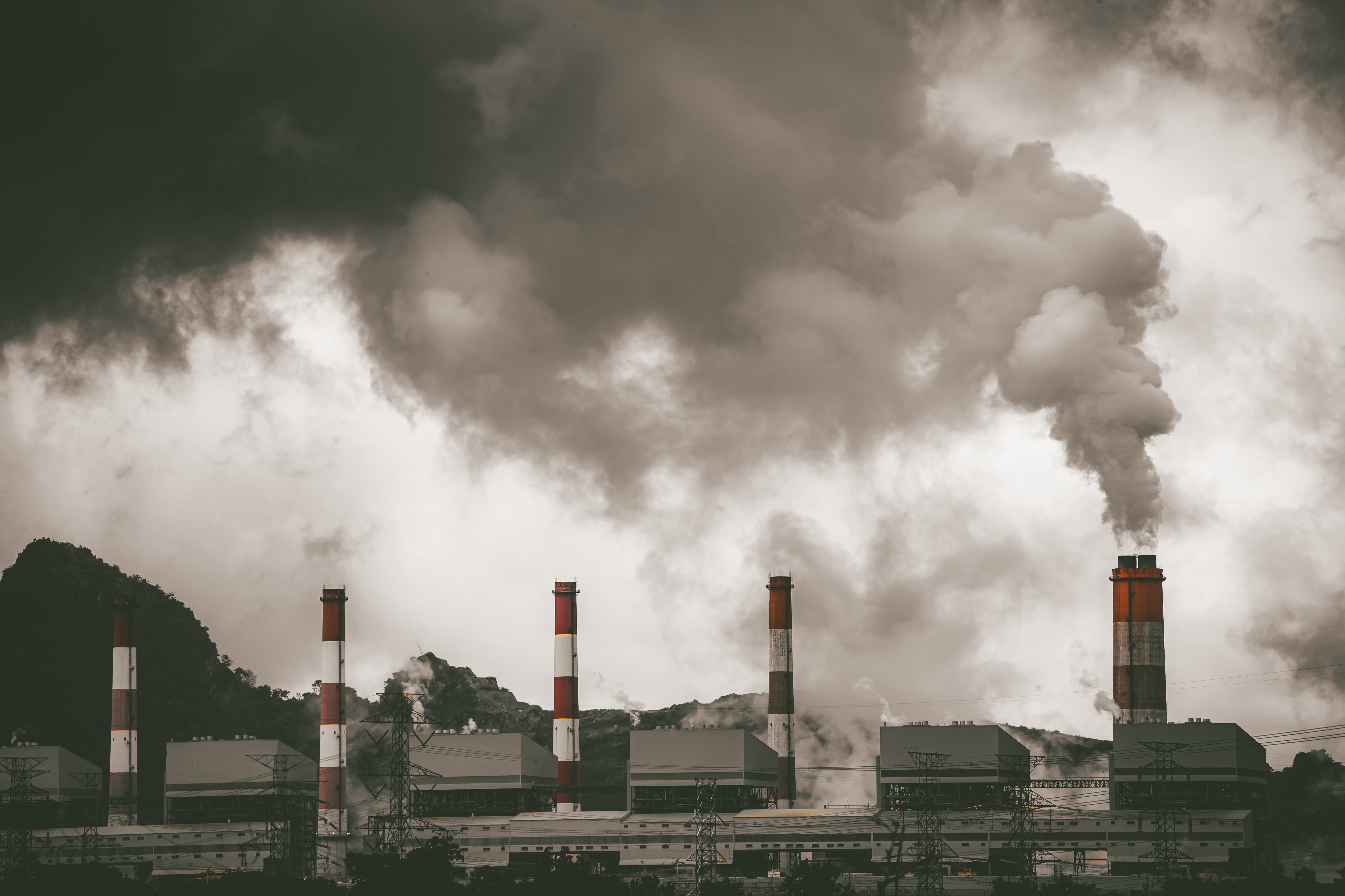 A sepia-toned image showing a factory with dark smoke billowing out of multiple smokestacks.