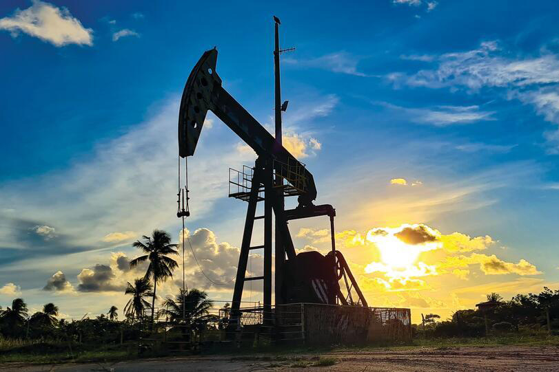 Pumping unit producing oil on land during sunset.