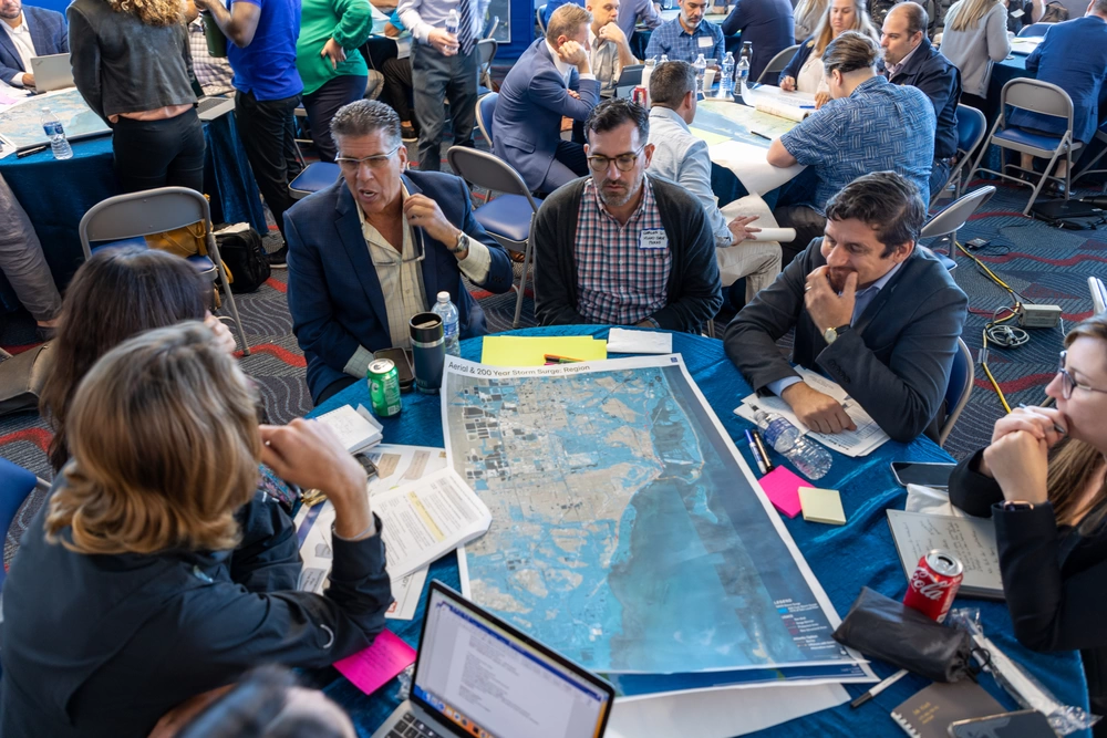 Group of individuals sitting at a table and looking at a map