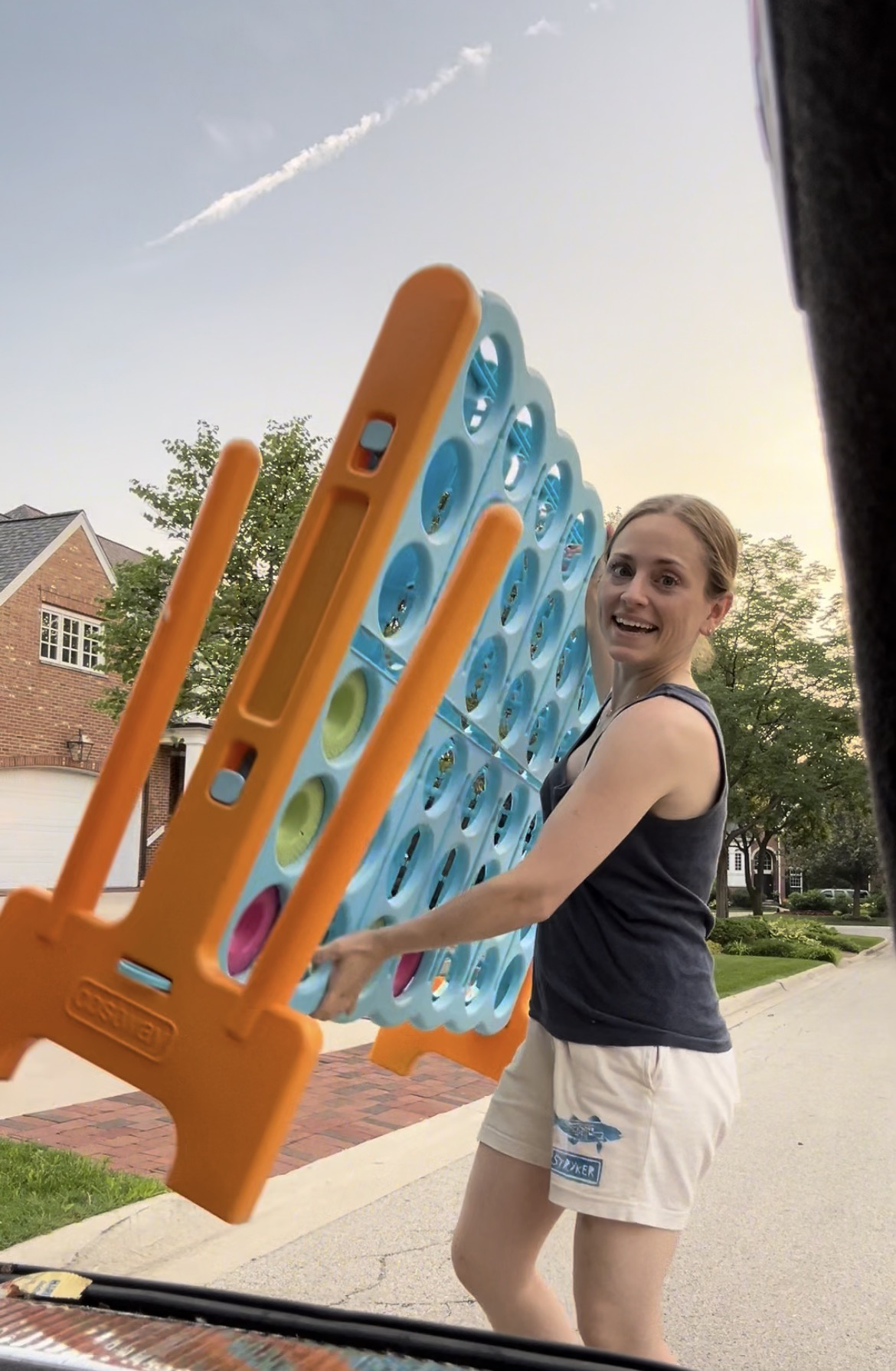 Claudia von Mallinckrodt holding a giant Connect 4 game board she pulled from someone's trash.