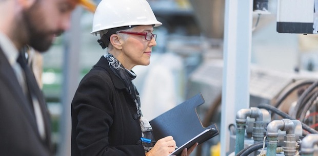Woman in business attire and hard hat in a factory