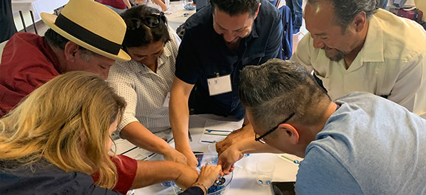 While playing the Groundwater Game, elected leaders compete to scoop the most glass beads into a small cup, which simulates pumping groundwater from a communal aquifer into a holding tank.