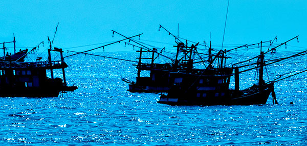 A group of 3 fishing boats in the ocean.