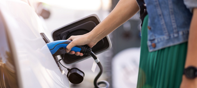 Woman charging electric vehicle