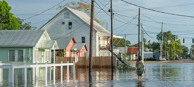 Flooding after Hurricane Laura with two people walking down a street in knee deep water