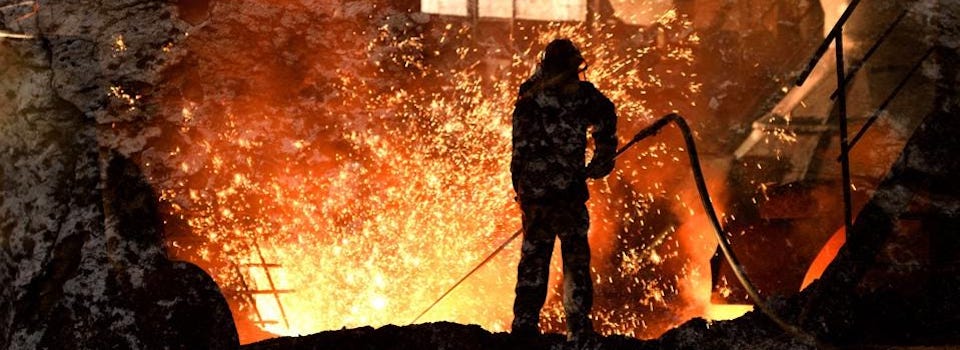 Person working in a steel mill’s blast furnace full of showering sparks