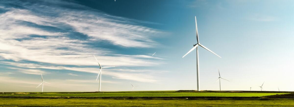Wind turbines across the landscape against blue sky.