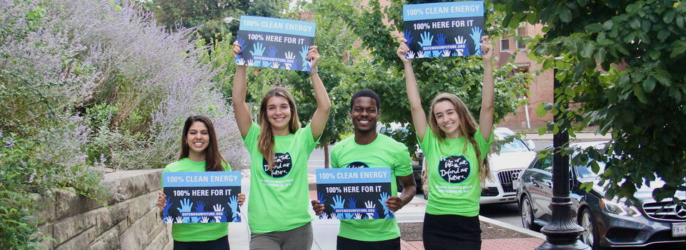 Young people holding signs supporting clean energy