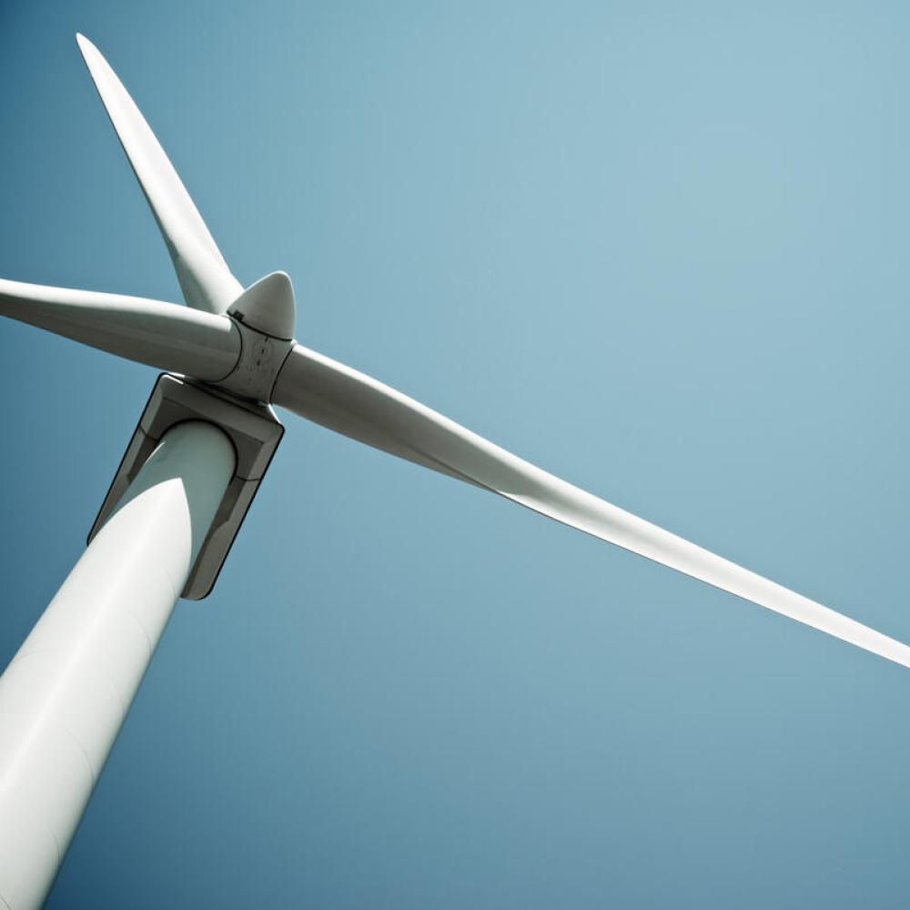 A windmill viewed from below, against a clear blue sky.