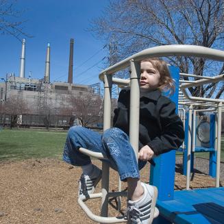 Girl playing at playground with power plant in the background
