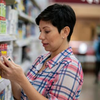 Middle-aged woman with short hair looking at a packaged in a grocery store