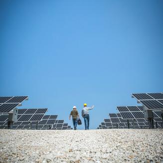 Clean energy workers walking between solar panels