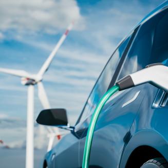 Electric vehicle charging with wind turbines in the background