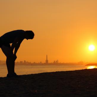 Horizon, person on beach bending over in heat
