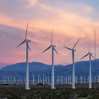 Wind turbines lined up with mountains in the distance