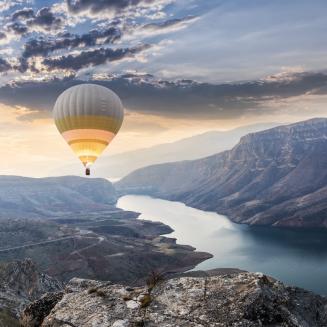 Hot air balloon flies over scenic river valley