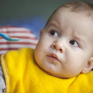 A baby refusing to eat from an offered spoon