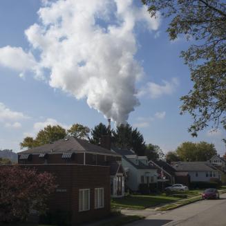 A residential street with backdrop of smoke billowing from power plant