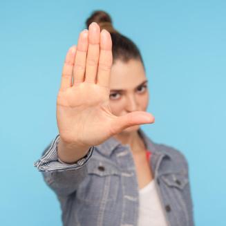 Woman holding her hand out in front of her face to indicate 'stop'