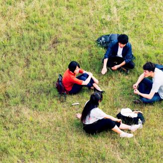 Four young people sitting in a field conversing