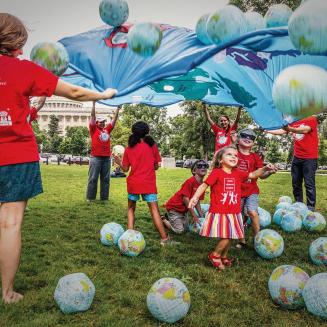 Moms playing with kids in Kids Clean Air Force t-shirts in front of the U.S. Capitol Building