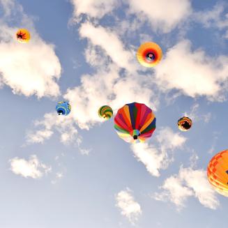 Colorful hot air balloons against a blue sky with fluffy clouds