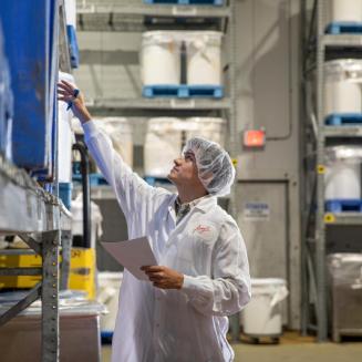 Santiago Toral, dressed in protective clothing, reaches up to shelves in a food factory