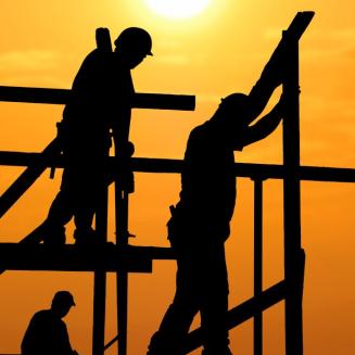 Construction workers silhouetted against the bright sun