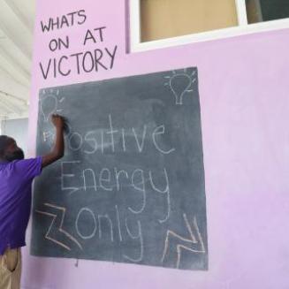 A student writes Positive Energy Only on a chalkboard