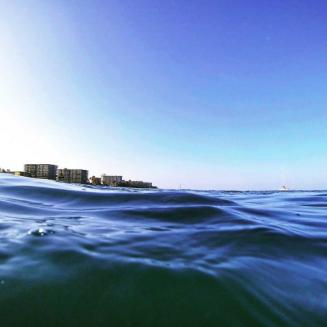 Photo of sea with distant view of urban skyline.