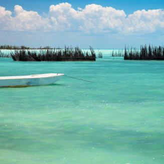 One small pleasure fishing boat and fish pens on calm turquoise blue sea north side Andros Island Bahamas