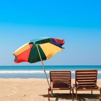 Two beach chairs on a sandy beach looking out over a blue ocean
