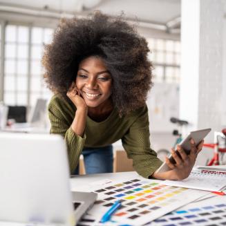 Black woman looking at computer and color proofs