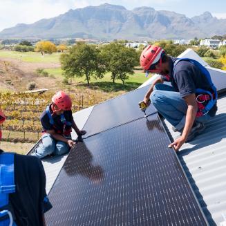 Workers installing solar panels on a roof in Cape Town, South Africa
